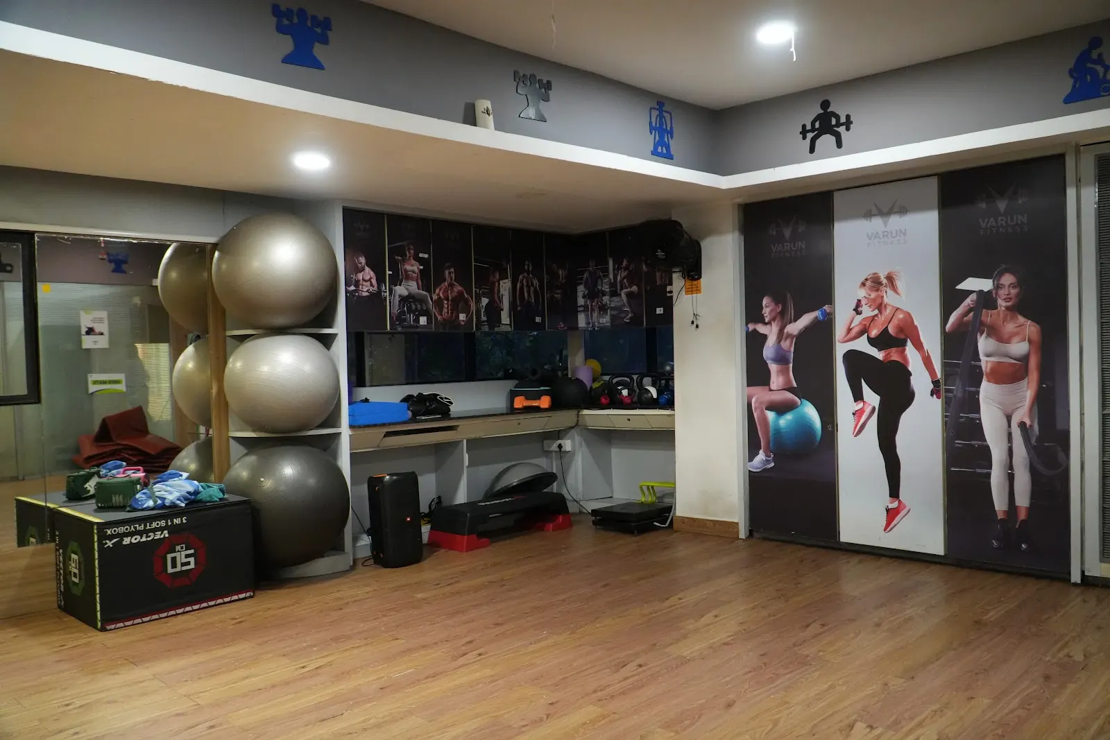 Open wooden-floor studio with exercise balls stacked against the wall